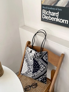 Detail of paisley canvas tote bag with black and white split pattern on a vintage chair