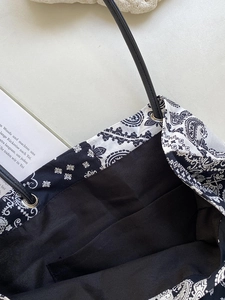 Detail of paisley print canvas tote bag featuring metal eyelets and a black inner pocket