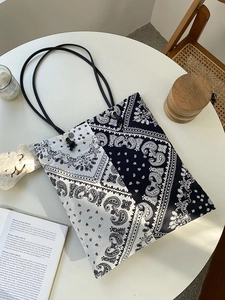 Top-down view of large canvas paisley tote bag on a white table with lifestyle decor