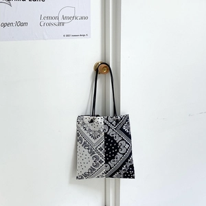 Detail of paisley canvas tote bag hanging on wooden knob with black rope strap