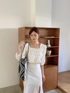 Detail of a black and white paisley canvas tote bag paired with a white textured outfit