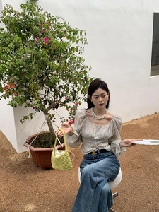 Detail of hand-woven cotton rope handbag paired with floral chiffon shirt and blue denim