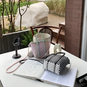 Detail of hand-woven crossbody bags with checkered patterns on a white garden table