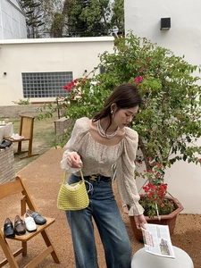 Handmade green woven handbag paired with a floral puff sleeve blouse and denim jeans
