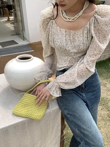 Close-up of a handmade green woven cotton rope tote bag held by a model in a floral top