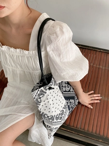 Detail of paisley canvas tote bag with slim black leather straps on a summer model