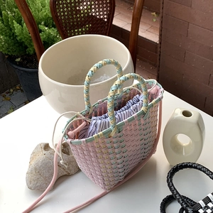 Detailed view of pink handwoven straw bag with striped drawstring lining and shoulder strap