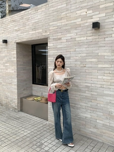 Close-up of pink handmade woven cotton shoulder bag held by a model in casual outfit