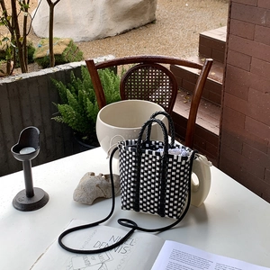 Detailed close-up of a handmade black and white checkered woven bag with drawstring liner