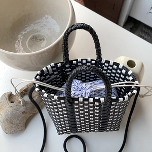 Handwoven black and white checkered straw bag with a blue striped drawstring liner