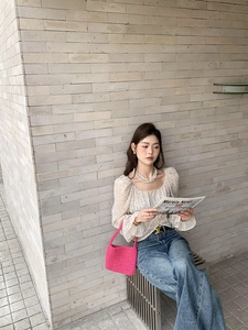 Detail of pink hand-woven cotton rope handbag styled with floral blouse and casual outfit