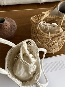 Close-up of handmade hollow woven beach bags with linen drawstring lining on wooden table