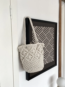 Detail view of handmade cream macrame woven texture on a stylish cylinder beach bag