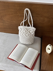Close-up of macramé shoulder bag with diamond weave pattern on a wooden bench