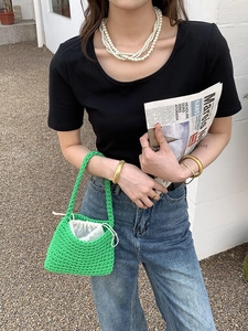 Detail of green handmade crochet tote bag with white drawstring lining held by a model