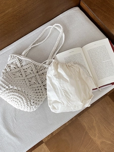 Detailed close-up of handmade beige woven beach tote with a removable cotton drawstring pouch