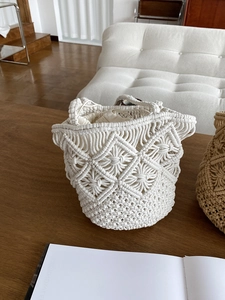 Detail of cream handmade woven straw bucket bag with drawstring liner on wooden table