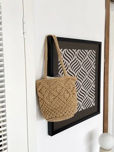 Detail of hand-woven hollow knit tote bag with beige crochet pattern and drawstring liner