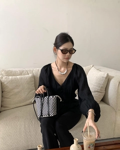 Close-up of checkered woven mini bucket bag with black strap and drawstring liner