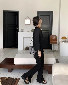 Detailed view of a mini black and white checkered straw crossbody bag on a model