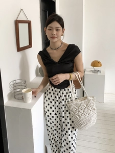 Detail of bohemian handmade hollow woven beach bag with black and white polka dot trousers