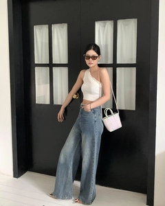 Street style view of white one-shoulder crop top paired with pink mini woven straw bag