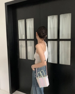 Detail of colorful macaron woven bucket bag with handles and a pink crossbody strap