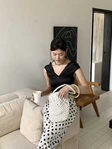 Detailed close-up of a white hand-woven straw bucket bag with elegant diamond knit patterns