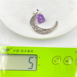 Macro detail of crescent moon pendant weighing 5g on an electronic scale for jewelry