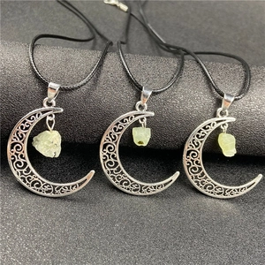 Close-up of hollow crescent moon pendant with light green gemstone on black background
