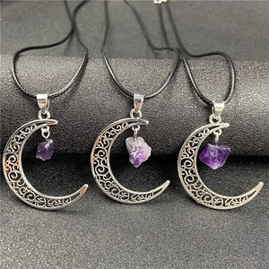 Close-up of hollow crescent moon pendant with raw purple amethyst on black wax cord