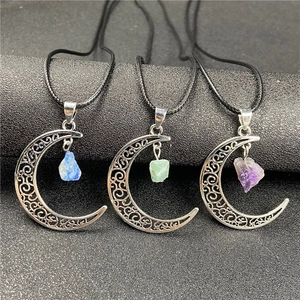 Detail of moon-shaped necklaces with hollow silver moons and colorful raw gemstone pendants