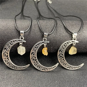 Detailed macro view of silver hollowed crescent moon pendants with raw yellow crystal stones
