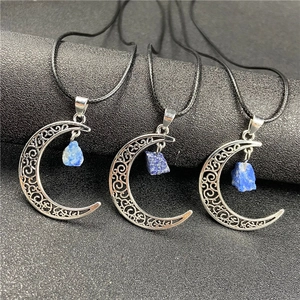 Detailed view of silver crescent moon pendants with raw blue gemstones on black cords