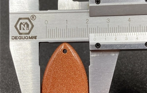 Macro shot showing 25mm width measurement of orange goldstone teardrop pendant