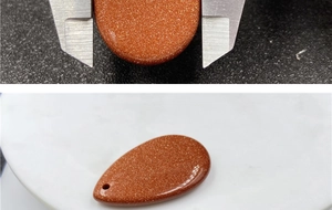 Detailed measurement of teardrop-shaped goldstone pendant with caliper tool