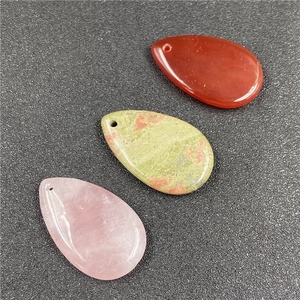 Three teardrop crystal pendants in rose quartz, red agate and unakite on grey texture