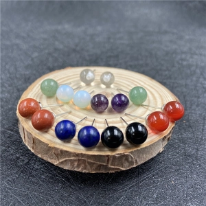 Sortierte Edelstein-Ohrstecker aus rotem Achat und Amethyst auf einer Holzscheibe