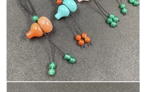 Close-up of assorted natural gemstone gourd pendants with woven black cords and beads