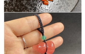 Detail of red agate gourd pendant with green bead and black hand-woven lanyard