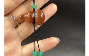 Macro detail of agate gourd pendant keychain with sparkling goldstone and green beads