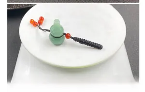 Close-up of a green jade gourd pendant being weighed on a digital scale for accuracy