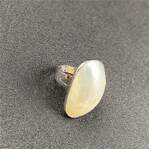 Close-up of large oval white mother of pearl ring with adjustable silver open band