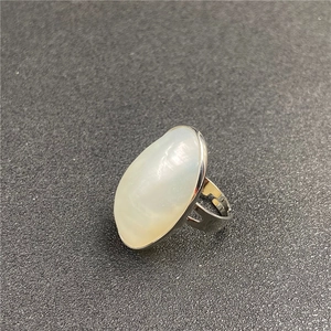 Top view of oval mother of pearl ring with adjustable silver band on dark grey surface