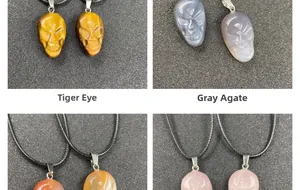Detailed view of hand-carved tiger's eye and grey agate skull pendants with braided cord