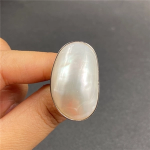 Macro detail of large oval mother of pearl ring with iridescent luster on a silver band