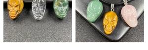 Detailed view of hand-carved skull pendants in tiger eye stone and crystal quartz