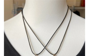 Detail of adjustable black braided leather cord necklace with silver trapezoidal pendant clasp