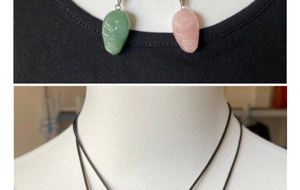Close-up of hand-carved alien skull pendants in green aventurine and rose quartz