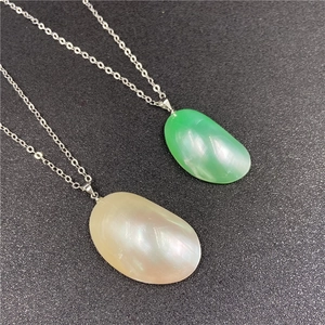 Détail de pendentifs en perles vertes et beiges sur d'élégantes chaînes en métal argenté